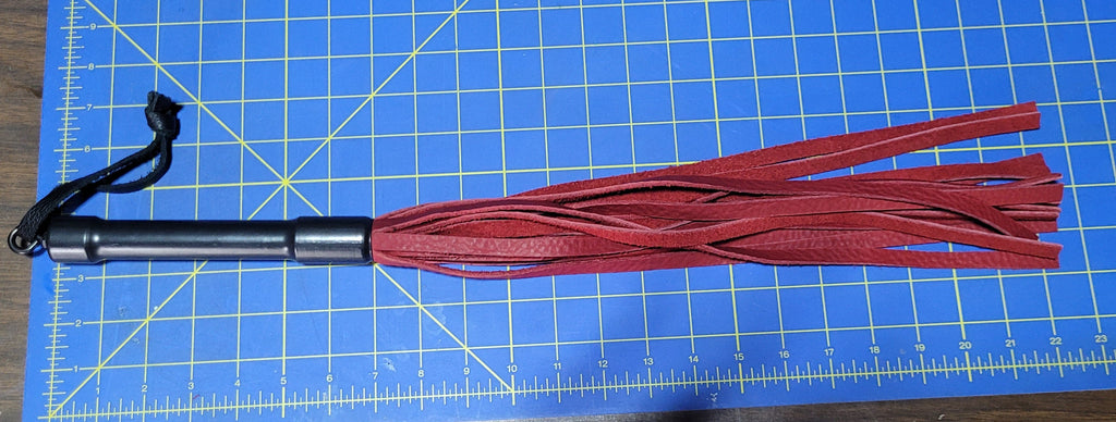 Red leather flogger on a blue cutting mat